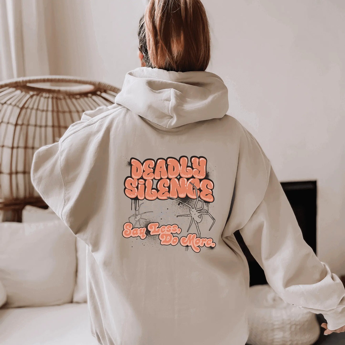 The back view of a girl wearing Urban Cookie's Move In Silence hoodie in Sand in a naturally lit living room